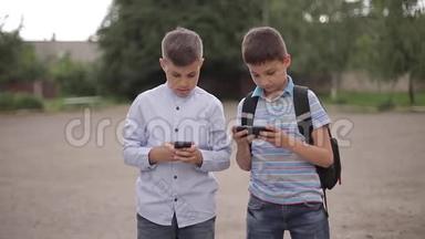 两个男孩放学后玩网络游戏。 小男孩微笑，用电话
